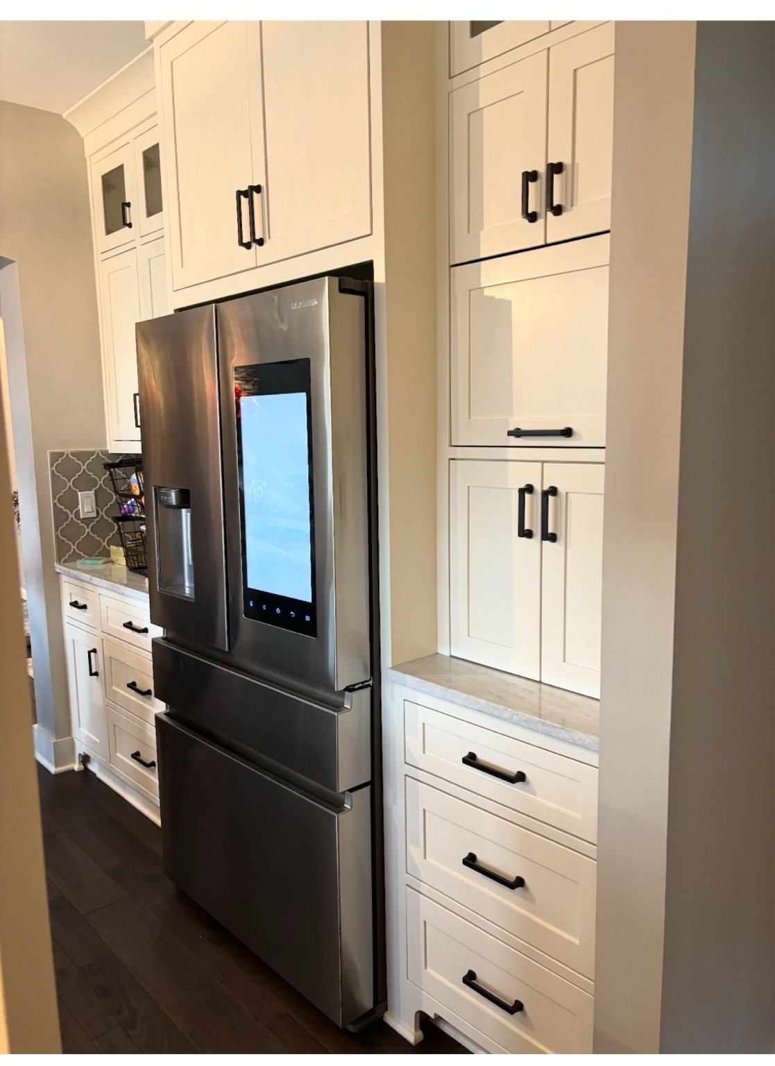 White floor-to-ceiling kitchen cabinetry around refrigerator